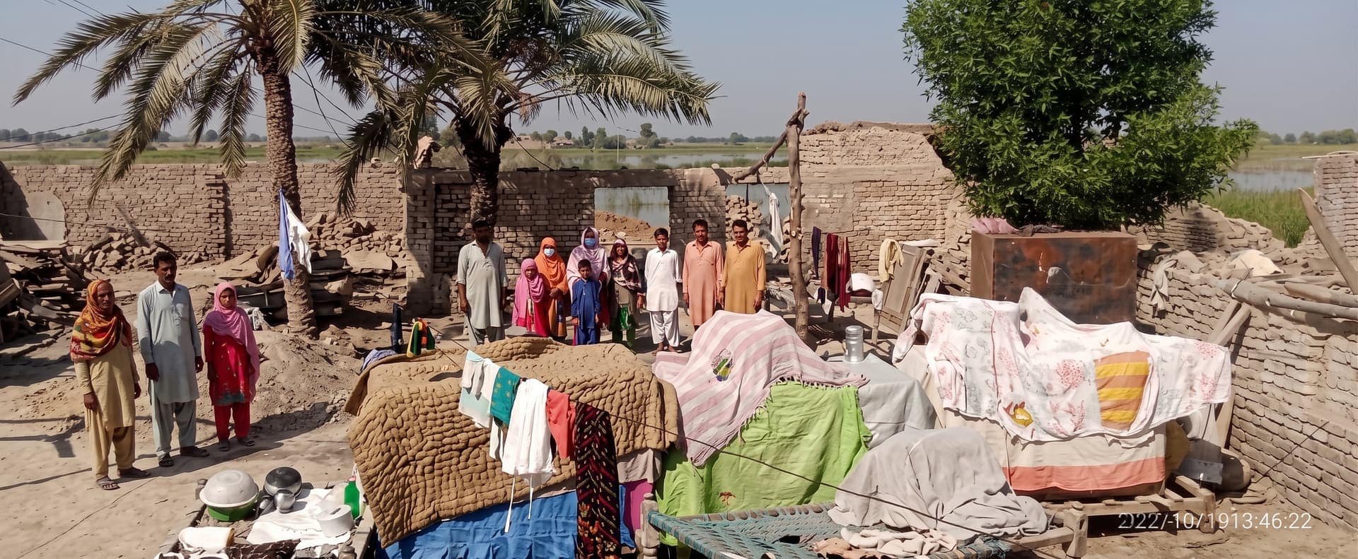 Families beside their flood-damaged homes in a village in Sindh