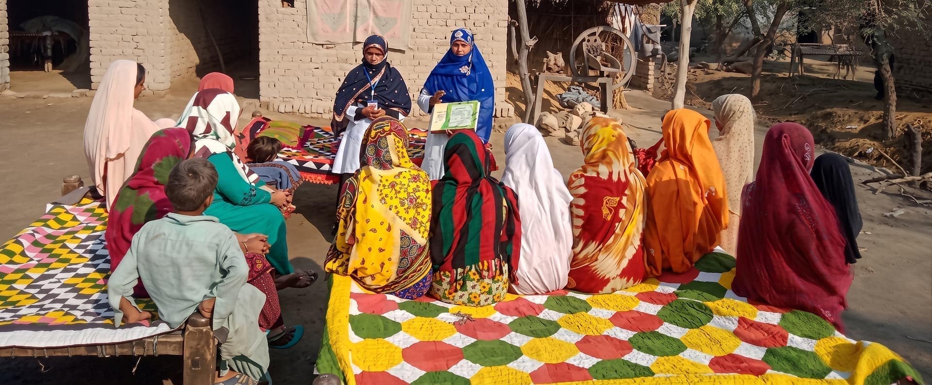 A Trust team member leading a community session with women and children in a village in Sindh